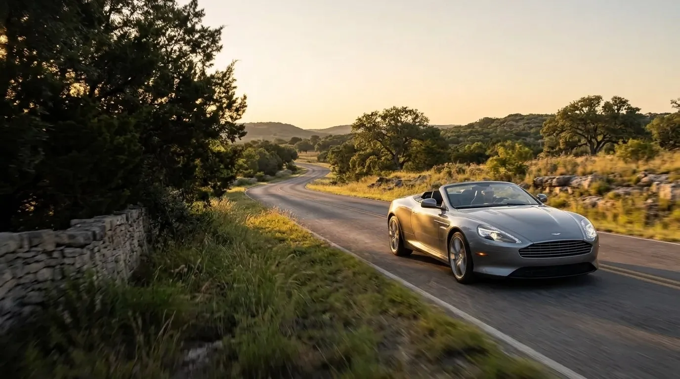 Texas Hill Country scenic drives with Kraft & Klasse Silver-grey Aston Martin DB9 Volante on a winding scenic road through the Texas Hill Country